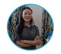 IT student stands among many colorful wires and stacks of hardware in a server room