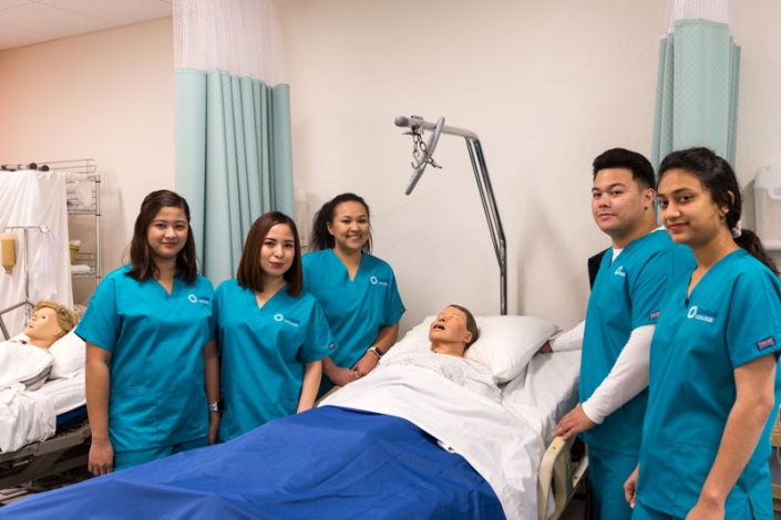 Diverse group of students smiling with a simulation mannequin.