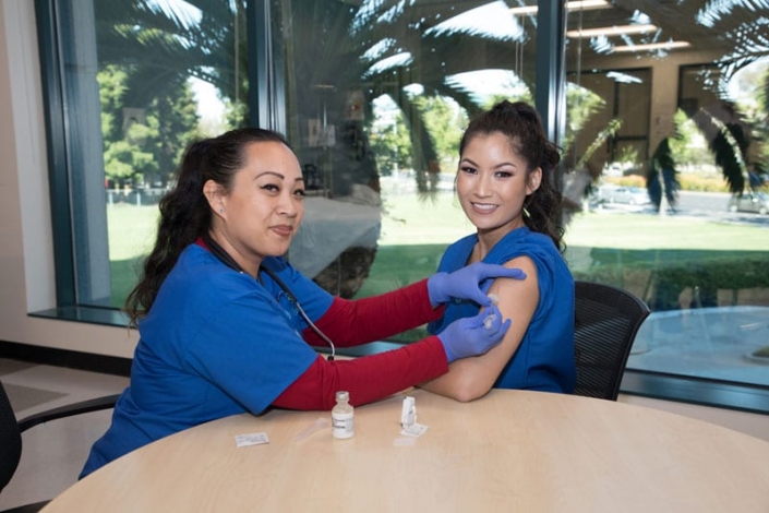 Nursing student practicing giving an injection to another student