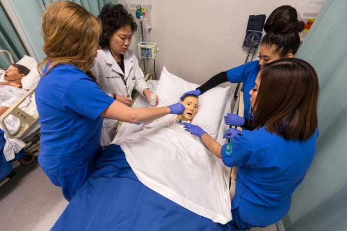 Nursing students practicing on a simulation mannequin who looks quite nervous