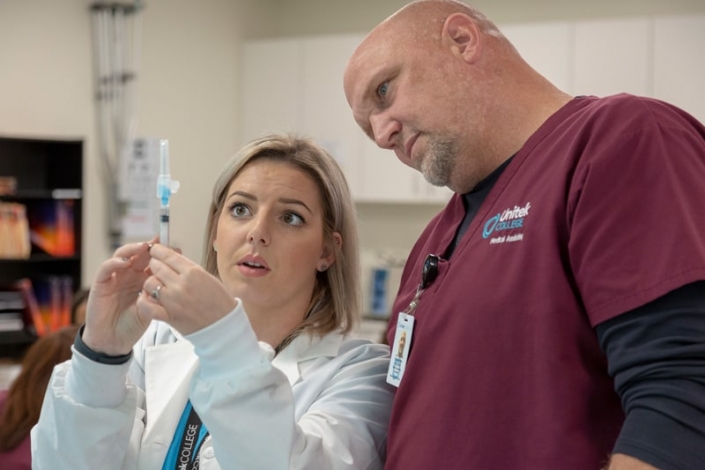 Instructor teaching a student about preparing an injection