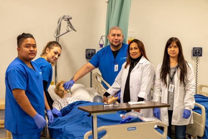 Grupo diverso de estudiantes de enfermería de pie cerca de un maniquí de simulación