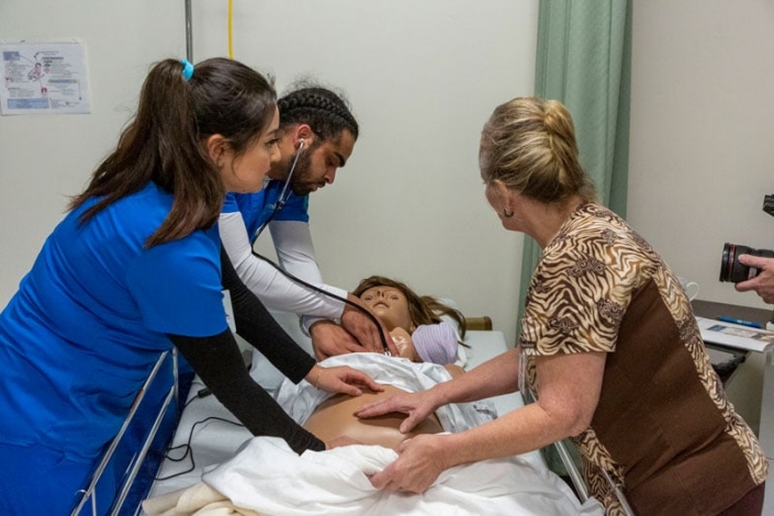 Estudiantes de enfermería practicando habilidades con maniquíes de simulación de madre y bebé