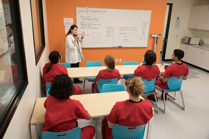 Nursing students sitting in a classroom listening to their instructor giving a lecture