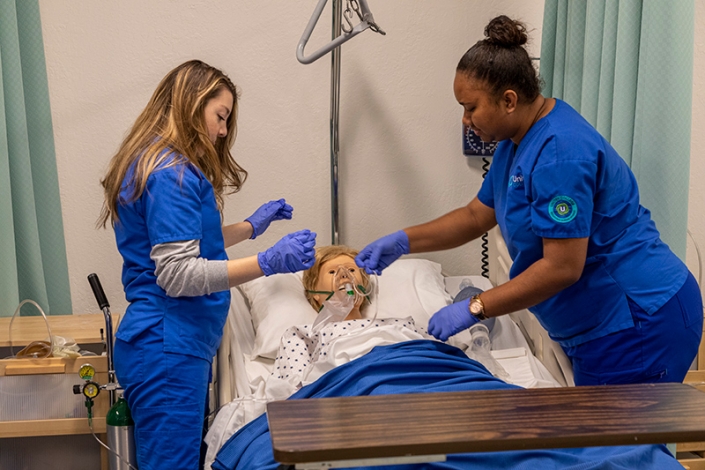 Two nursing students practicing skills on a simulation mannequin