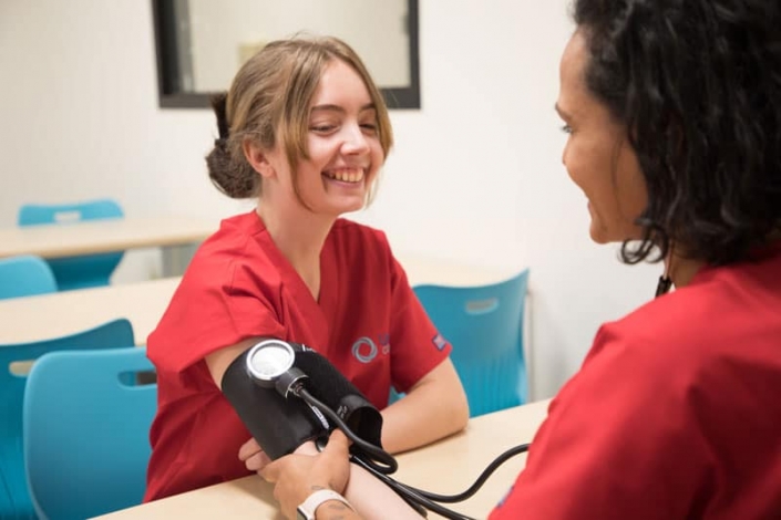 Nursing student practicing taking vitals on another student