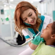 Profesional sonriente ayudando con un examen dental