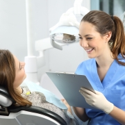 Dental student in blue scrubs working with a patient and filling out paper work