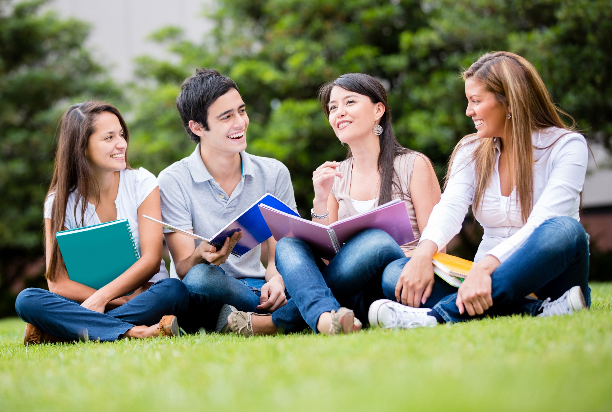 Feliz grupo de estudiantes sentados en la hierba