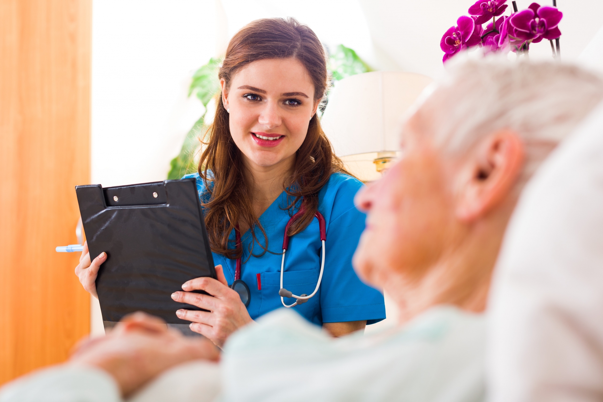Nurse with a clipboard talks to an elderly patient