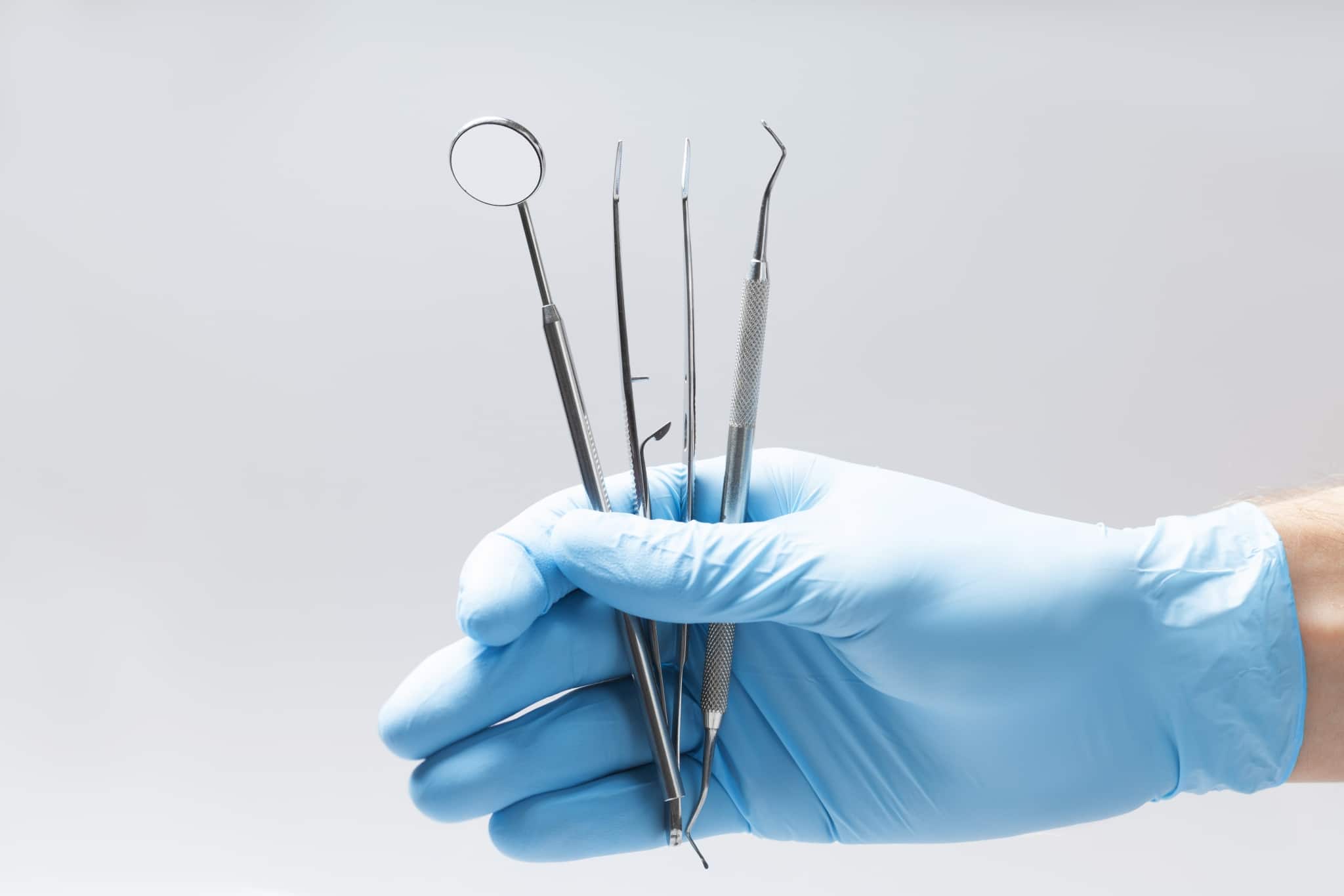 Gloved hand holding dental instruments