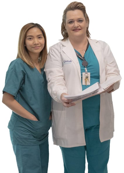 Student in scrubs standing with her instructor