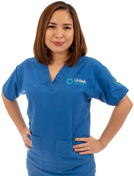 A nursing student in blue scrubs standing with hands on her hips