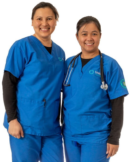 Two nursing students in blue scrubs standing side by side