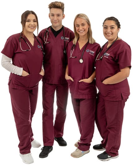 0G5A1352-530 Four students in maroon scrubs standing together with hands in their pockets
