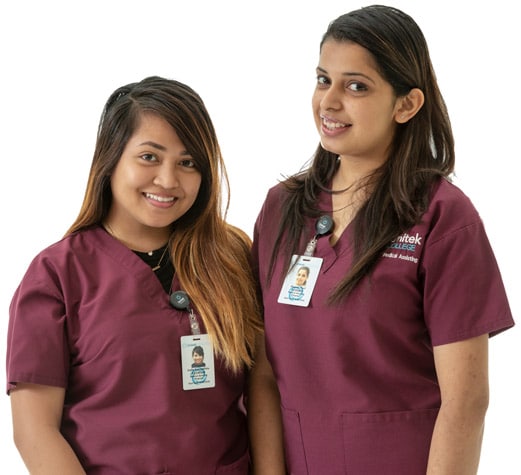 Two nursing students in scrubs standing side by side and smiling