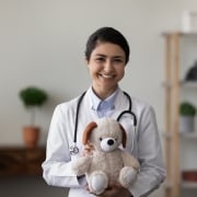 Profesional médico indio sonriente con un oso de peluche