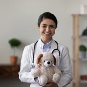 Smiling Indian medical professional with a teddy bear