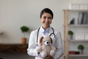 Smiling Indian medical professional with a teddy bear