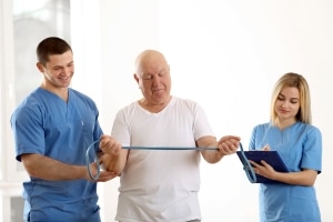 Physiotherapists with a patient using bands