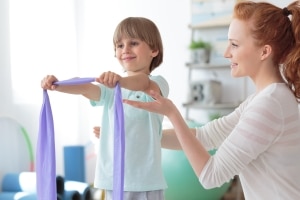 Physical Therapist Assistant with young patient using bands