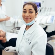 Smiling dental professionals with a patient in an exam room