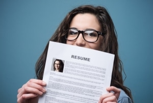 Primer plano de una mujer con gafas sosteniendo su currículum