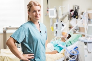 Blonde nurse standing next to an intubated patient