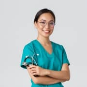 Smiling Asian nurse in scrubs against a grey backdrop