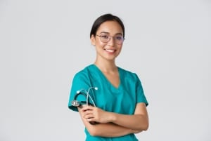 Smiling Asian nurse in scrubs against a grey backdrop