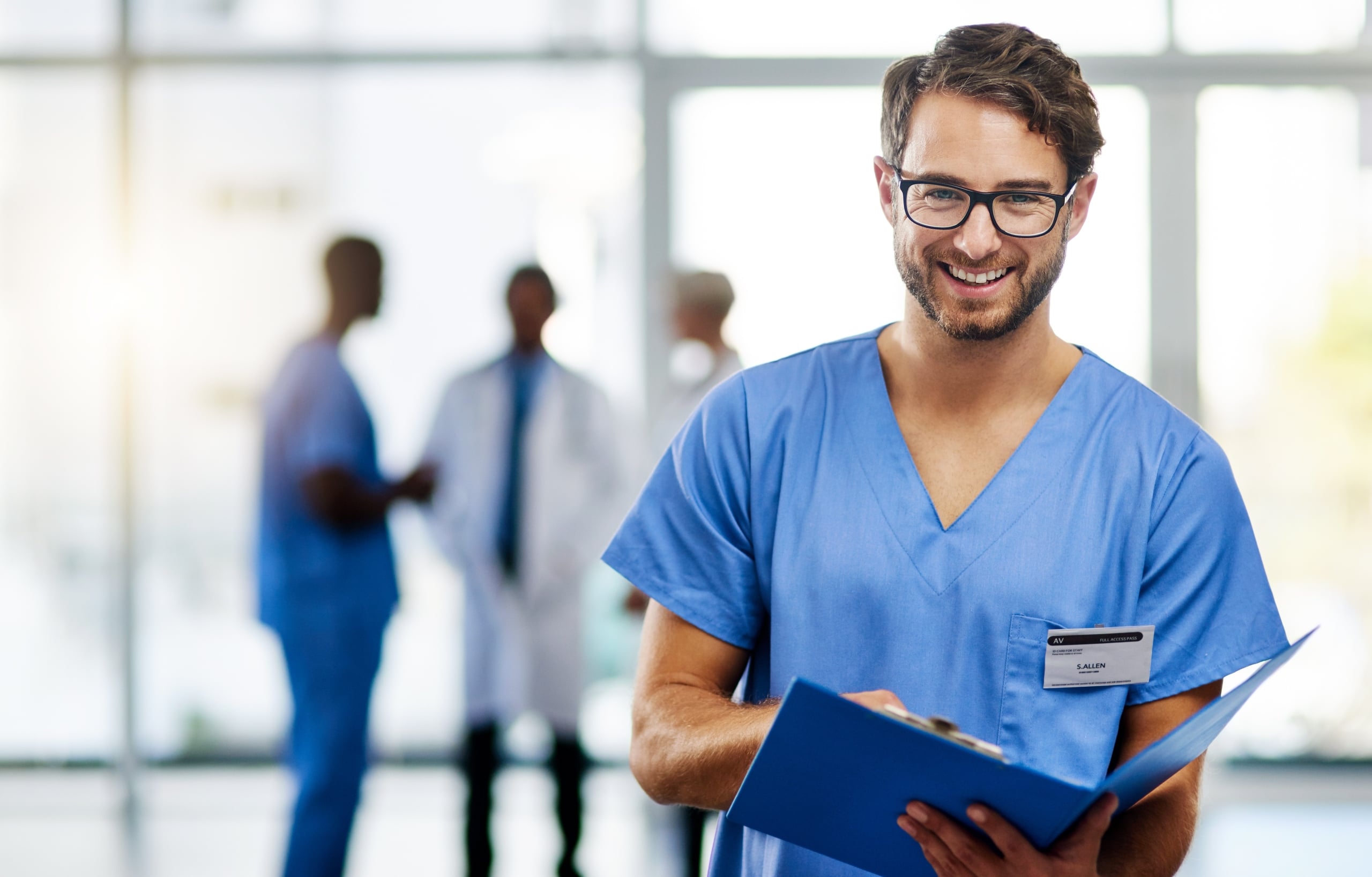 Smiling male nurse in glasses holding an open folder