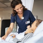 Female nursing smiling at a young boy in a hospital bed