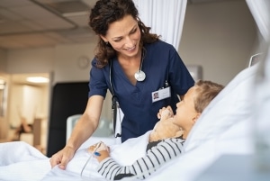 Female nursing smiling at a young boy in a hospital bed