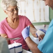 Nurse wrapping an elderly woman's hand in gauze