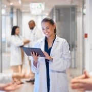 Nurse smiling at a tablet in a hospital hallway