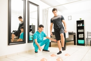 Profesional de fisioterapia ayudando a un hombre a sortear obstáculos en el suelo