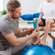 Physical therapy professional applying medical tape to a young patient