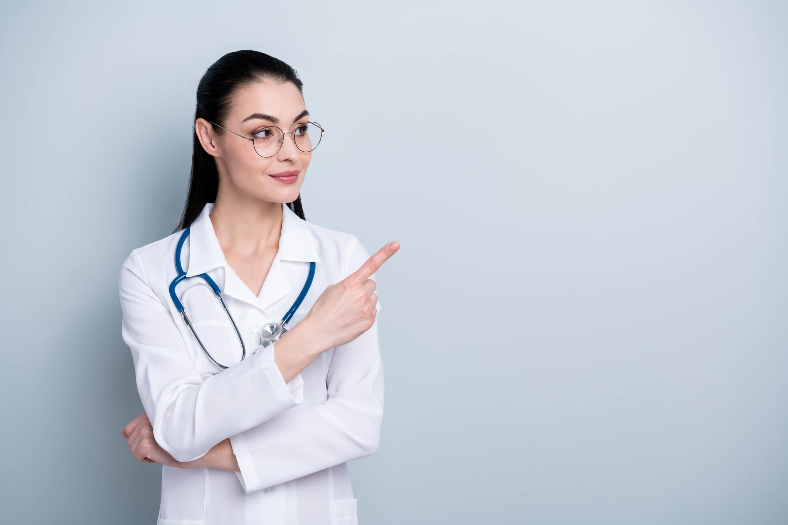 Medical professional pointing to the side against a solid backdrop
