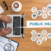 Medical professional typing on a laptop next to public health virtual symbols