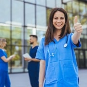 Nurse standing outside the hospital with a thumbs-up sign