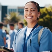 Happy nursing student standing outside with a tablet