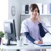 Young female medical professional in scrubs answering the phone