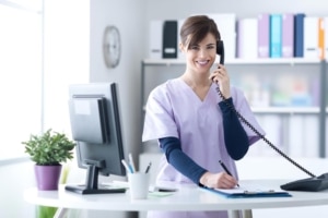 Young female medical professional in scrubs answering the phone